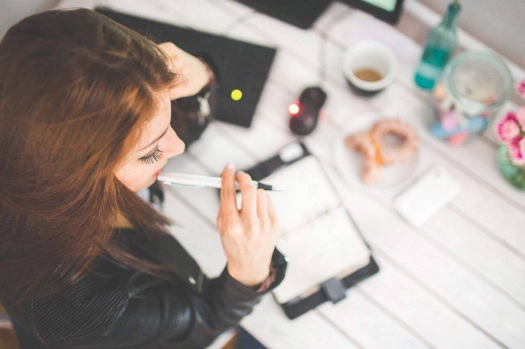 Eine junge Frau am Schreibtisch mit Stift und Notizblock