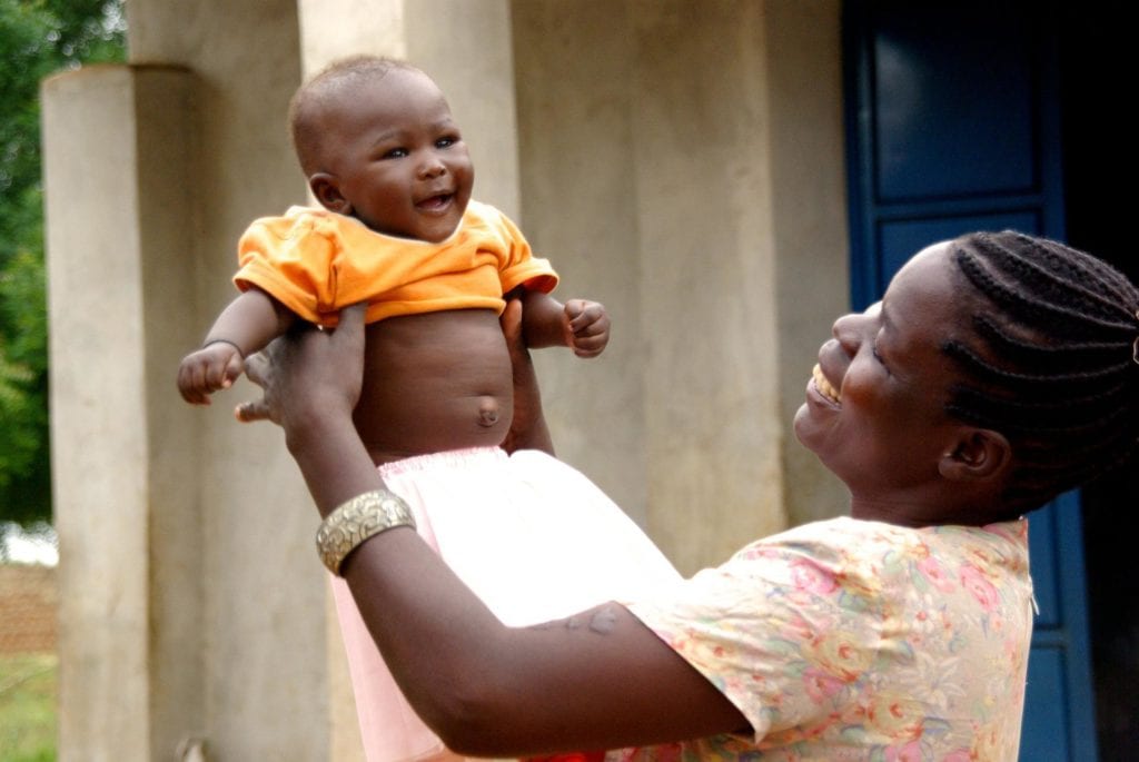 Eine afrikanischer Mutter hält ihr Baby in die Luft, HIV