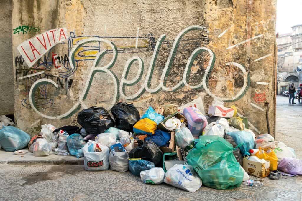 Abgestellter Müll vor einer städtischen Wand mit Schriftzug