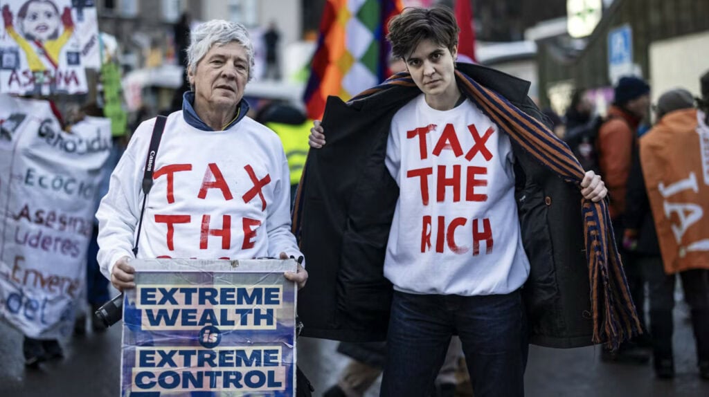 Marlene Engelhorn und ein weiterer Mann mit weißen Pullis an, auf denen steht, tax the rich. Marlene Engelhorn und ein weiterer Mann mit weißen Pullis an, auf denen steht, tax the rich.