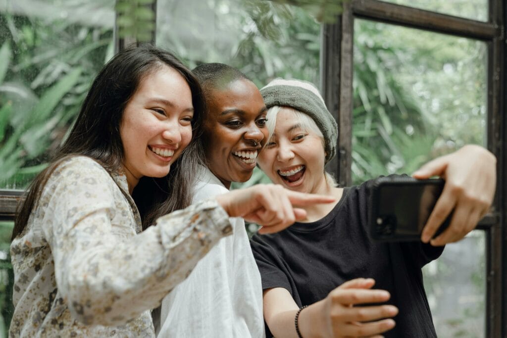 Drei Menschen lachen, während sie ein Selfie machen.