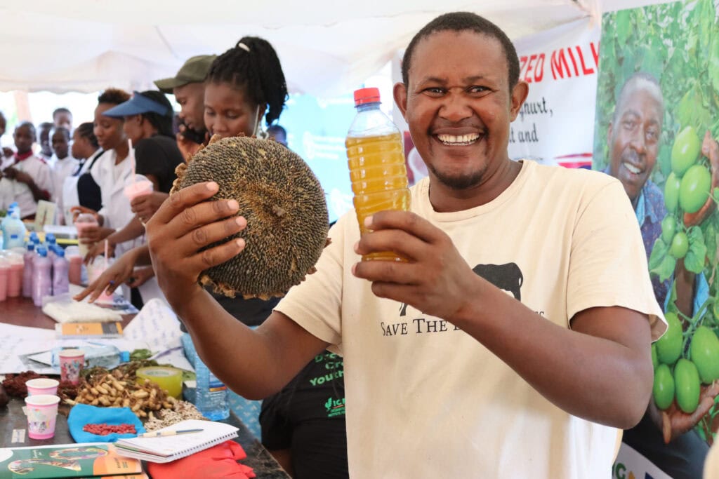Nashon Mwagharo displaying a sunflower head and oil at a local agriculture exhibition © Victor Ndobi Save the Elephants