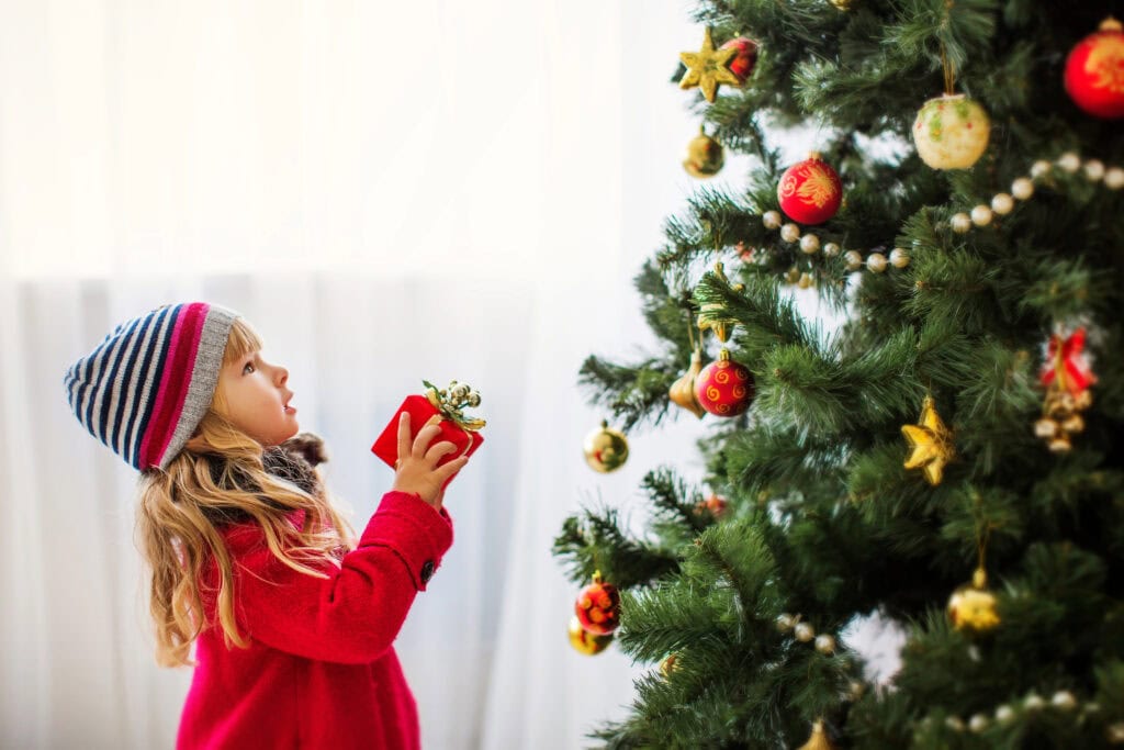 Mädchen mit Geschenk am Weihnachtsbaum. Der Weihnachtsbonus macht es möglich. Credits: https://depositphotos.com/de/photo/girl-near-christmas-tree-merry-christmas-happy-new-year-34890293.html