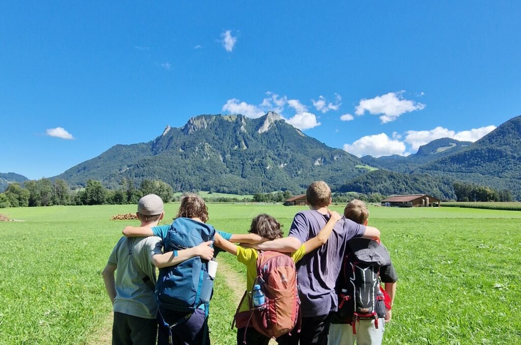 HERAUSFORDERUNG einfach machen -Kinder stehen zusammen als Gruppe und blicken auf einen Berg in der Ferne.